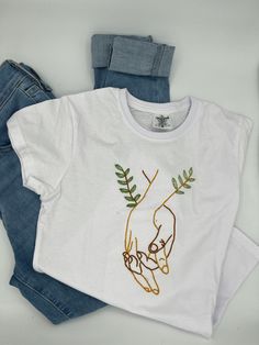 Hand-embroidered cotton t-shirts. There are 6 variations with sizes S to L. Five tshirts have a bag with handles with the same design. It is possible to buy just the tshirt or the tshirt and bag set. For handle bags visit https://www.etsy.com/pt/listing/1737997279/saco-de-alcas-bordado-a-mao-saco Casual T-shirt With Multicolor Embroidery And Logo, White T-shirt With Embroidered Graphics As Gift, White Embroidered T-shirt For Gift, White Embroidered T-shirt As Gift, White T-shirt With Machine Embroidery As Gift, White T-shirt With Machine Embroidery For Gift, Summer Everyday T-shirt With Embroidered Text, Casual T-shirt With Floral Embroidery For Gift, Casual T-shirt With Machine Embroidery As Gift