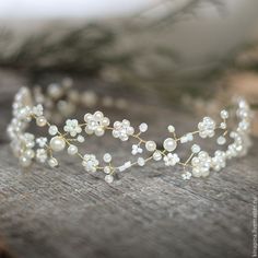 a close up of a tiara on a wooden surface with flowers and pearls around it