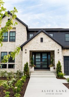 a large white brick house with two garages and black doors on the front door