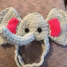 a crocheted elephant hat with ears on it's head is shown in front of a gray shirt