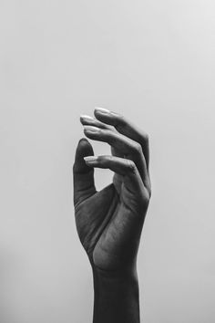 a person's hand with their fingers up in the air, against a gray sky