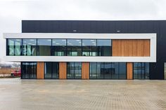 an empty parking lot in front of a large building with lots of windows and doors