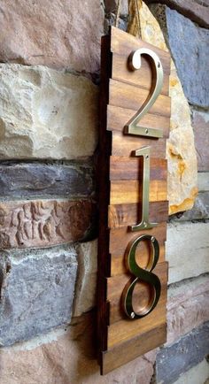 a wooden sign with the number two on it next to a stone wall in front of a brick wall