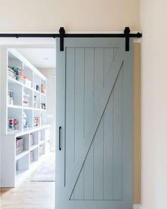 an open sliding door in a room with wooden floors and white walls, leading to a pantry