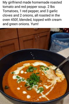 a bowl of tomato soup with cheese and spinach on top, in front of a kitchen counter