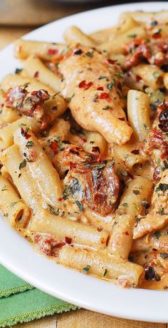 a white plate topped with pasta covered in sauce and chicken breast pieces on top of it