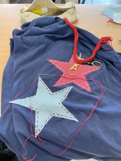 a pair of scissors on top of a blue shirt with red and white stars attached to it