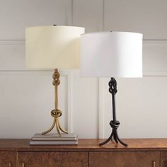 two lamps sitting on top of a wooden table next to a lamp with a white shade