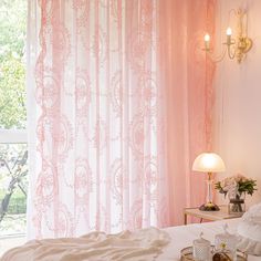 a bed sitting under a window next to a lamp and a table with food on it