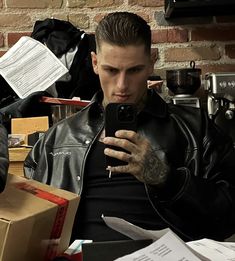 a man with tattoos is looking at his cell phone while sitting in front of boxes