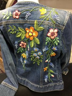 a denim jacket with embroidered flowers on it