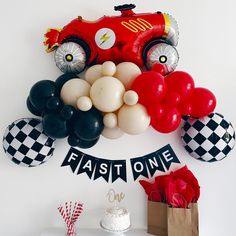 a birthday party with balloons and cars on the wall, including a race car cake