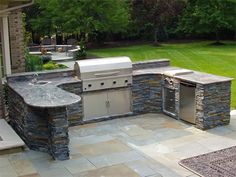 an outdoor kitchen with stone counter tops and grill