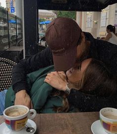 a man and woman kissing in front of coffee cups