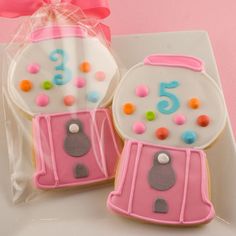 two decorated cookies sitting on top of a white plate next to a pink bag filled with candy