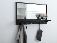 a mirror hanging on the wall next to a towel rack and potted plant in front of it