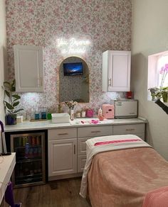 a room with a bed, sink and mirror in it that has flowers on the wall