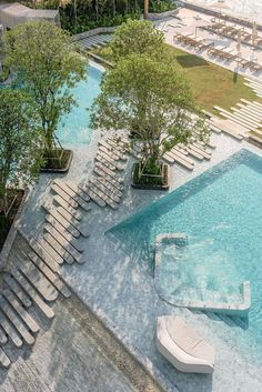 an aerial view of a swimming pool with lounge chairs and trees in the foreground