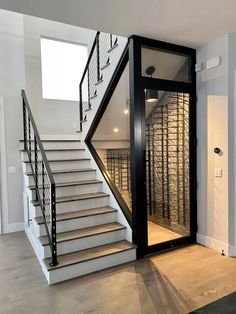 an empty room with stairs leading up to the second floor and wine cellar behind it