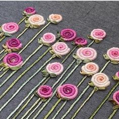 pink and white flowers are arranged in rows on a gray tablecloth with green stems