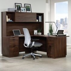 an office desk with a laptop computer on top of it and a book shelf above the desk