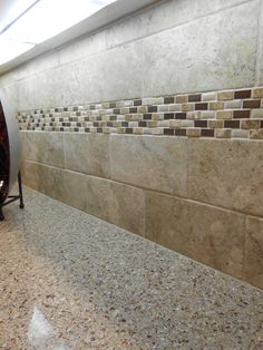 a tiled wall in a public restroom with no shower curtain or curtains on the window sill