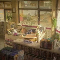 a room filled with lots of books next to a window covered in signs and posters