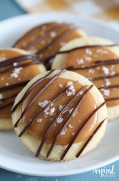 three cookies with chocolate drizzled on them and sitting on a white plate