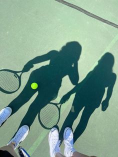 two people standing on a tennis court holding racquets next to each other