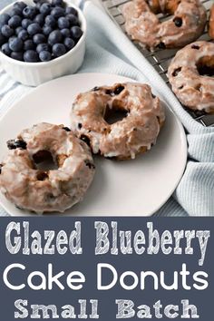 glazed blueberry cake donuts are on a white plate and next to a bowl of blueberries