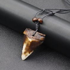 a brown and white animal's tooth hanging from a black rope on top of a table