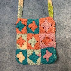 a multicolored crocheted purse sitting on top of a blue carpet covered floor