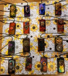 many different cell phones are hanging on a wall with wires attached to them and some flowers in the background