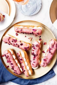 pink glazed donuts with white frosting and sprinkles on a plate