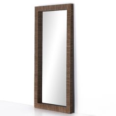 a mirror sitting on top of a white counter next to a wall mounted shelf with a wooden frame