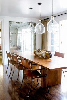 a dining room table with six chairs and a large mirror on the wall behind it