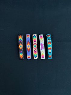 four bracelets are lined up on a black surface, each with different colors and designs