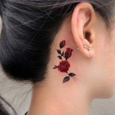 a woman's behind the ear tattoo with red roses