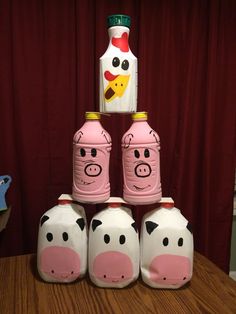 four pink piggy jars sitting on top of a wooden table next to a bottle