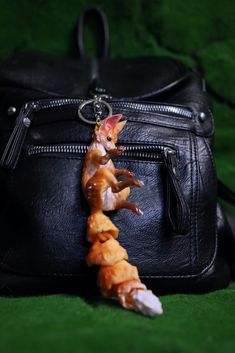 a piece of food sitting on top of a black bag next to a handbag