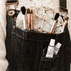 a person holding a pocket full of makeup brushes and other items in their back pocket