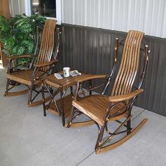 three wooden rocking chairs sitting next to each other on top of a cement floor near a potted plant