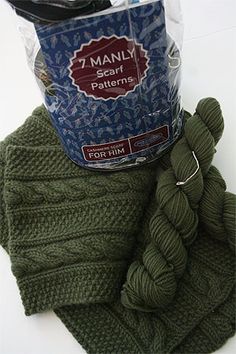 two green knitted items are sitting on top of each other, one is wrapped in plastic