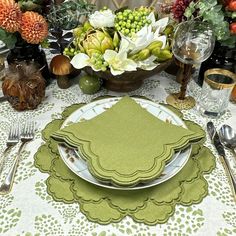 a table set with plates, silverware and green napkins for an elegant dinner