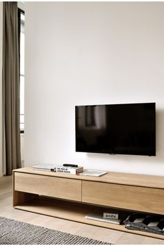 a flat screen tv sitting on top of a wooden entertainment center next to a window