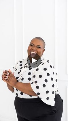 a woman in black and white polka dot shirt posing for the camera with her hands on her hips