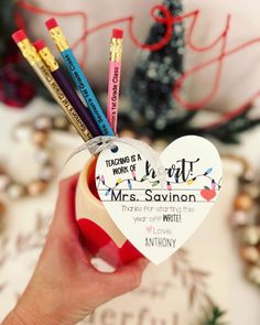 a hand holding a heart shaped ornament with pencils in the shape of a teacher's work of mrs savinon