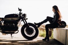 a woman sitting on a bench next to a motorcycle