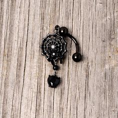 Black Gem Black Spiderweb Halloween Reversible Dangle Belly Ring If you're ready to get into the spirit of Halloween then you will love this 14 gauge navel jewelry with scary style! Made with a 3/8" black plated over 316L surgical grade stainless steel curved barbell, this reversible navel ring features a spiderweb dangle charm with a black gem spider as well as a black gem heart dangle charm that is perfect for trick or treating or a gothic ball.Specifications14 Gauge (1.6mm), 3/8" (10mm), Blac Gothic Piercings For Halloween Gift, Spooky Adjustable Black Jewelry, Adjustable Black Spooky Jewelry, Black Piercings For Halloween Gift, Gothic Black Dangle Body Jewelry, Halloween Black Jewelry With Charms, Black Halloween Jewelry With Charms, Nickel-free Black Emo Jewelry, Adjustable Black Gothic Body Jewelry