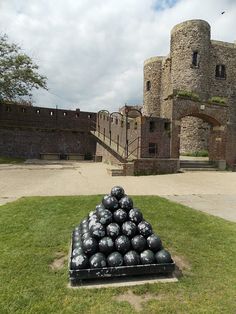 a pile of black balls sitting on top of a green field next to a castle